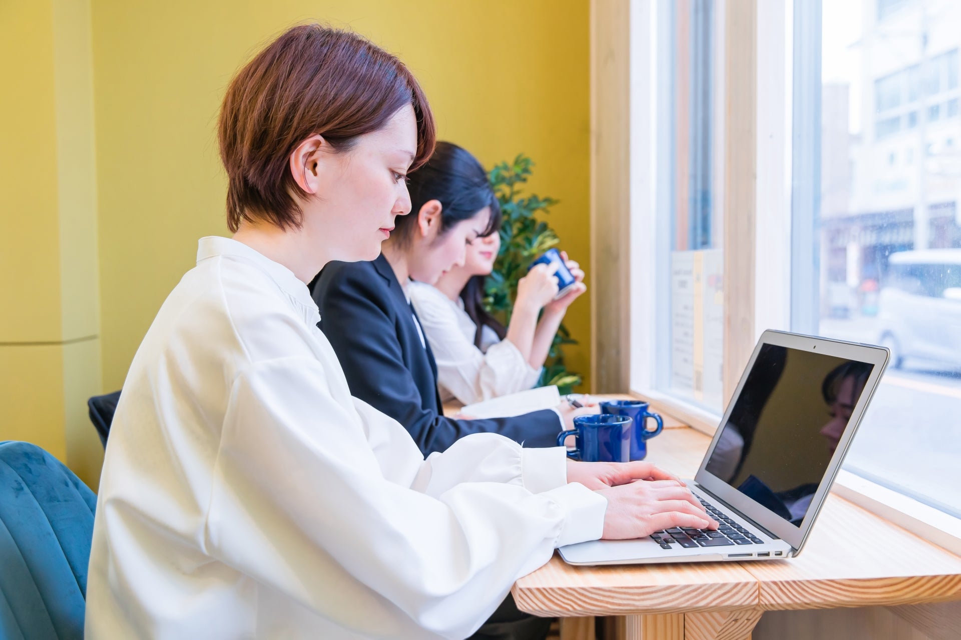 カフェでノートパソコンを使う若い女性