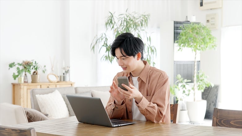 パソコンとスマートフォンを使う男性
