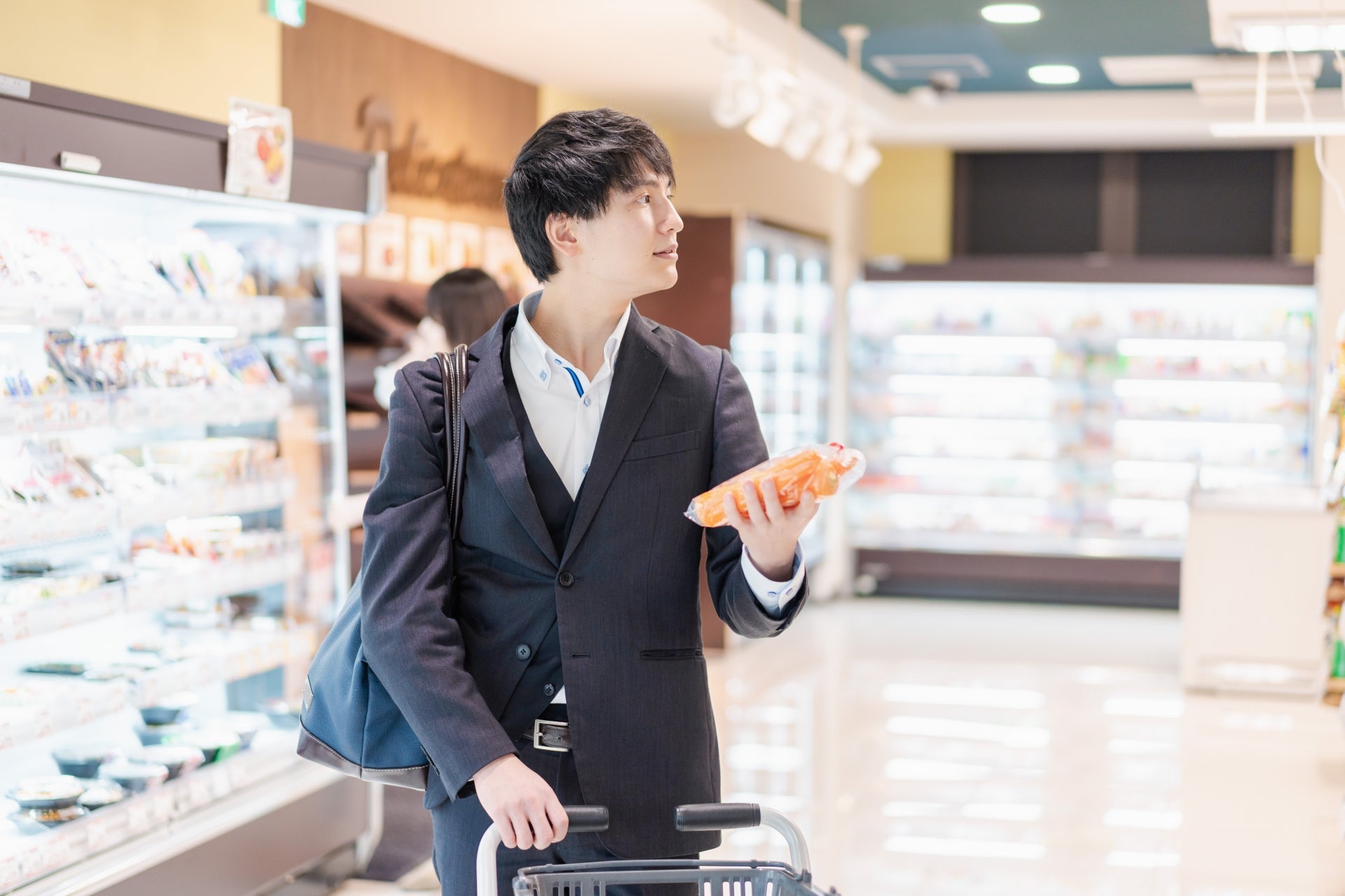 スーパーで野菜を買うビジネスマン