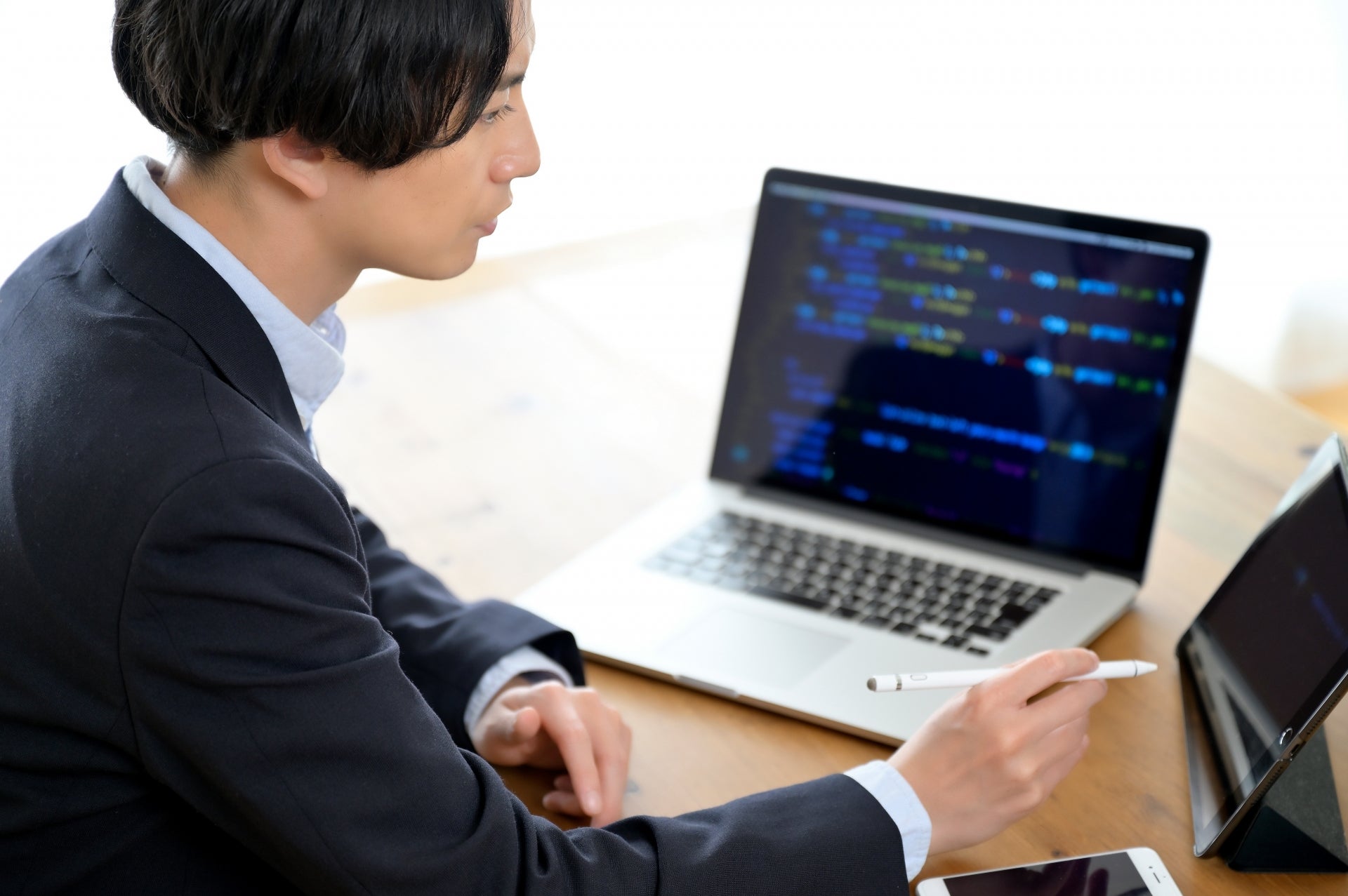 ダイニングでノートパソコンとタブレット端末を使って仕事をする男性